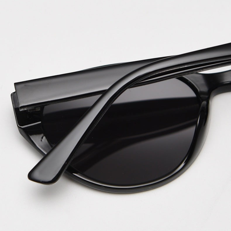 Close-up side detail shot of retro cat eye sunglasses with glossy black TR90 frame, showing smooth temple texture and curved lens rim on plain white background